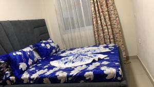 a bed with a blue comforter and pillows on it at Appartement meublé , Bonamoussadi, Douala-Vanguard's signature Suite in Douala