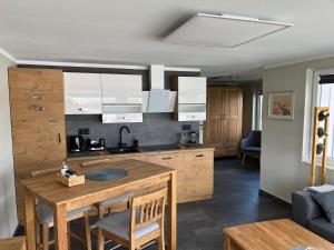 a kitchen with a wooden table with chairs and a couch at Bungalow direkt am See - Toilette und Dusche in separatem Gebäude in Berlin