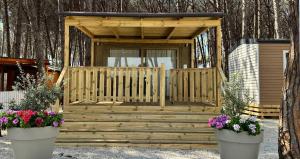 a wooden cabin with two flower pots in front of it at Camping Village Mare Pineta in Paestum