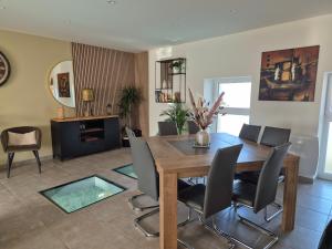 a dining room with a wooden table and chairs at Villa Terre & Mer avec piscine intérieure proche Cabourg in Escoville