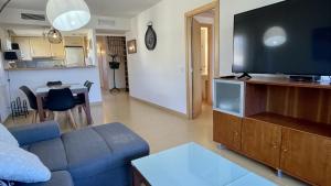 a living room with a blue couch and a flat screen tv at Riells Blau C302 in L'Escala