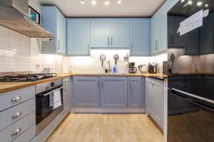 cocina con armarios azules y suelo de madera en Stylish Chic Retreat: 1-bed, Near Canary Wharf en Londres