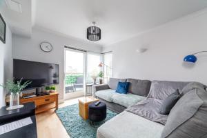 uma sala de estar com um sofá cinzento e uma televisão em Stylish Chic Retreat: 1-bed, Near Canary Wharf em Londres