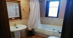 La salle de bains est pourvue d'un lavabo, d'une baignoire et d'une fenêtre. dans l'établissement Villa y Corte - Colegiata, à Ampudia