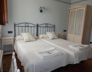 - une chambre avec un grand lit blanc et 2 serviettes dans l'établissement Villa y Corte - Colegiata, à Ampudia