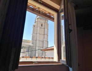 une fenêtre avec vue sur une tour d'horloge dans l'établissement Villa y Corte - Colegiata, à Ampudia
