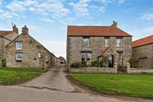 an old stone house with a road in front of it at Goldfinch cottage in Newton