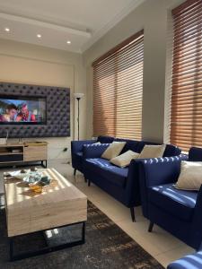 sala de estar con sofás azules y TV en Swiss Cottage Bhurban, en Bhurban