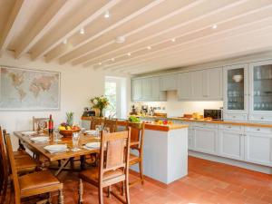 una cocina con mesa y sillas y una cocina con armarios blancos. en 4 Bed in Corwen 88868, en Corwen