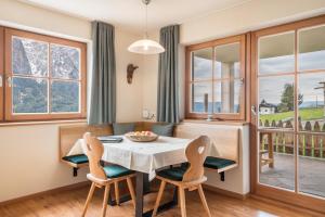 Un comedor con mesa y sillas y ventanas. en Ronsolhof Ortler, en Siusi