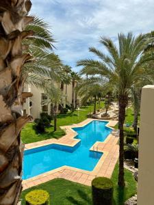 a pool with palm trees next to a building at Casa Del Sol by Rental Hero in San Javier