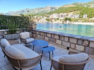 eine Terrasse mit Stühlen und Tischen und Blick auf das Wasser in der Unterkunft Kazanegra Exclusive Apartments in Sveti Stefan