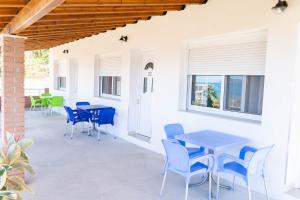a patio with blue tables and chairs and windows at Vila Aliaj in Vlorë