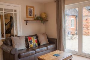 a living room with a leather couch and a sliding glass door at Dale Cottage in Ironbridge