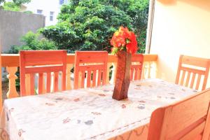 uma mesa com um vaso com uma flor vermelha em Kiriri SYMPA Home em Bujumbura