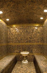 a tiled bathroom with a toilet and two benches at HOTEL DIOR in Dushanbe