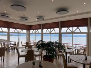un restaurante con mesas y sillas y vistas al océano en Hôtel Des Princes, en Amphion les Bains