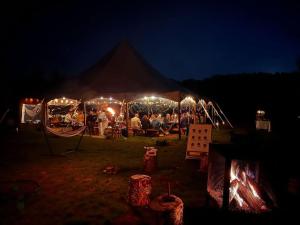 a group of people standing under a tent at night at Hôtel UNIQ - Domaine Saint-Bernard in Mont-Tremblant