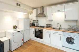 a kitchen with white cabinets and a washer and dryer at Elephant&Castle Apartments By Sleepy in London