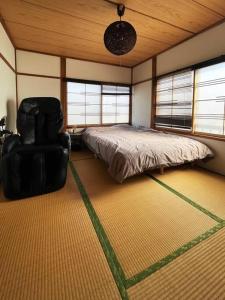 um quarto com uma cama e uma cadeira em アラン別邸自然溢れる呼人の一軒家 em Yobito
