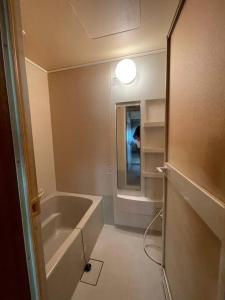 ein Bad mit einer Badewanne und einem Spiegel in der Unterkunft アラン別邸自然溢れる呼人の一軒家 in Yobito