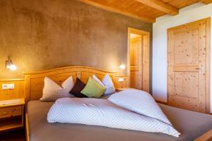Schlafzimmer mit einem Bett mit weißer Bettwäsche und Kissen in der Unterkunft Ronsolhof Santner in Seis am Schlern