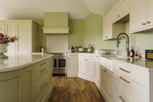 uma cozinha com armários brancos e pisos em madeira em Mellguards, 4-Bed Country Cottage, in Howtown em Watermillock
