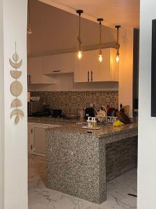 a kitchen with a granite counter top and white cabinets at Havre de Douceur Maison Cosy Confort et Style in Dakhla