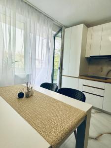 a kitchen with a table and some chairs and a window at Golden Apartament in Şelimbăr