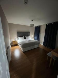 a bedroom with a white bed and a wooden floor at Blacklion prime location apartment in Blacklion