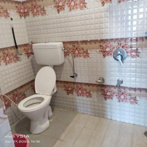 a bathroom with a toilet and flowers on the wall at Elizabeth paying guest house Tangmarg gulmarg in Gulmarg