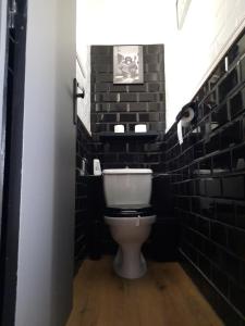 カリー・ル・ルエにあるLe Paradis Bleuの白いトイレと黒レンガの壁が備わるバスルーム