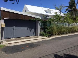 a white house with a fence and a garage at Case Taapuna in Saint-Joseph