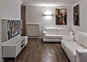 a living room with a white couch and a tv at Casa Micisca - Pescasseroli Centro in Pescasseroli