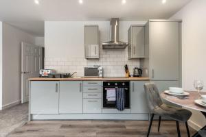 a kitchen with white cabinets and a table and chairs at Contemporary Studio Apartment in Central Rotherham in Rotherham