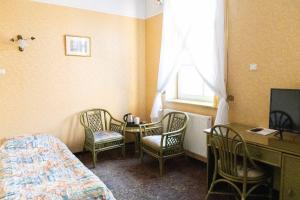 a bedroom with a bed and chairs and a table and a window at Hotel Calisia in Kalisz