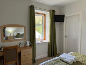 a bedroom with a bed and a desk and a mirror at Lochranza Country Inn in Lochranza