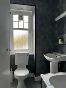 a bathroom with a toilet and a sink and a window at Lochranza Country Inn in Lochranza