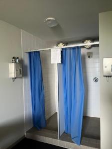 a shower with blue curtains in a bathroom at Bungalow direkt am See - Toilette und Dusche in separatem Gebäude in Berlin +16 photos