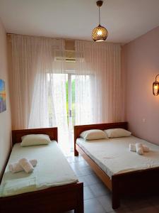 Duas camas num quarto com uma janela em Adamidis Apartments em Paralia Skotinas