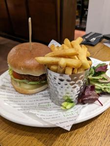 a plate with a hamburger and french fries on a table at Lochranza Country Inn in Lochranza