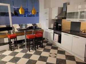 a kitchen with white cabinets and red bar stools at Hafen Deern in Flensburg