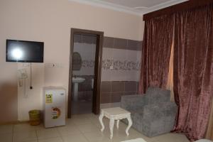 ein Wohnzimmer mit einem TV, einem Stuhl und einem Tisch in der Unterkunft الراقية للوحدات السكنية المفروشة in Medina