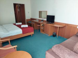 a room with a bed and a desk with a computer at Hunguest Hotel Aqua Sol in Hajdúszoboszló