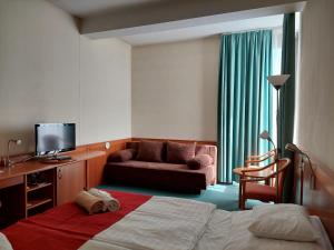ハイドゥソボスローにあるハンゲスト ホテル アクア ソルのベッドとソファ付きのホテルルーム
