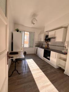 a kitchen with white cabinets and a table in it at Appartement Cosy - Plein centre in Marseille