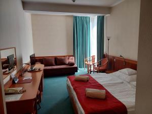 ハイドゥソボスローにあるハンゲスト ホテル アクア ソルのベッド2台とソファが備わるホテルルームです。