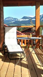 a chair on a deck with a table and mountains at Bergbauernhof Wechs in Ofterschwang
