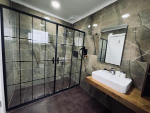 een badkamer met een glazen douche en een wastafel bij Treekos Suite Hotel in Arnavutköy