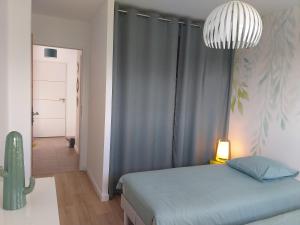 ein Schlafzimmer mit einem Bett und einer Hängeleuchte in der Unterkunft Le 101 - Plage du Dossen à Santec à 1.5 km in Santec